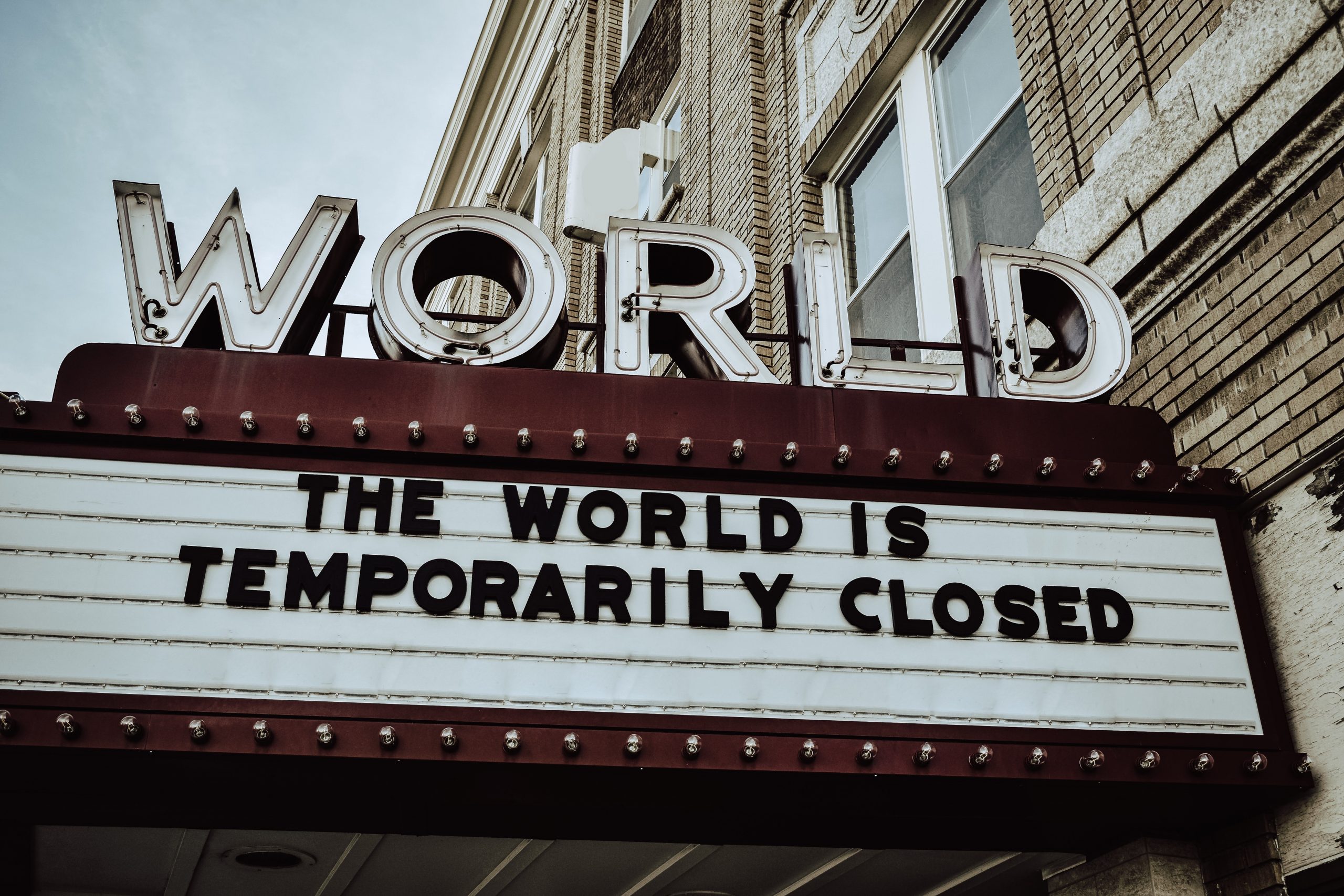 A sign on a theater called "WORLD" reads "The World is temporarily closed."